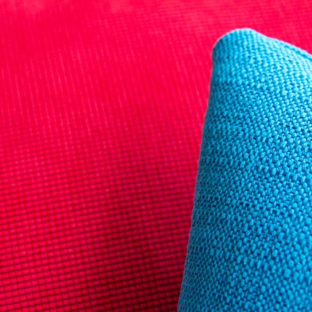 Alt text: Close-up of two textured fabrics, one bright red and one teal blue, showing woven patterns.Wind Armor Fabric:
