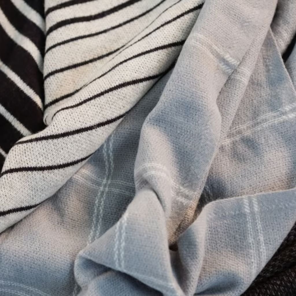 Sustainable Wool Fabric: Natural Warmth with a Green Promise 12 Alt text: Close-up of folded textiles, showing a black-and-white striped fabric beside a light grey plaid-like material with visible texture.
Sustainable Wool Fabric:
