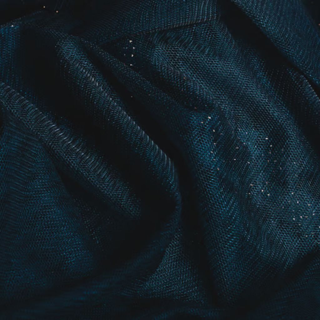 Winter Shield Active Fabric: Warm, Dry & Active Wear Guide 10 Alt text: Close-up of draped, dark teal fabric with a shimmering net-like texture and small gold specks catching the light, forming soft folds and shadows.
Winter Shield Active Fabric: