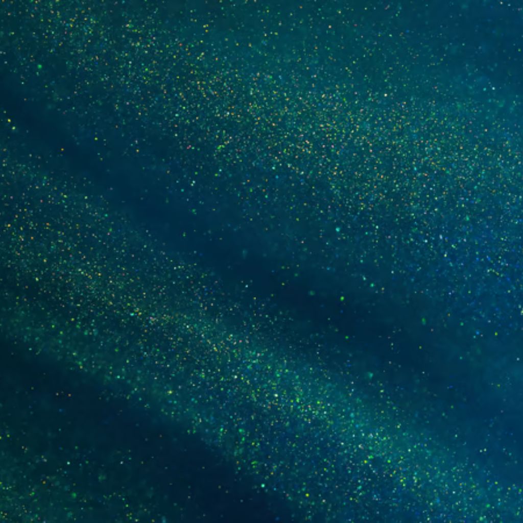 Winter Glow Supreme Fabric: High-Performance Winter Textile 10 A close-up of dark blue fabric with tiny scattered glittering specks in green and yellow, creating a shimmering, star-like effect. Winter Glow Supreme Fabric:
