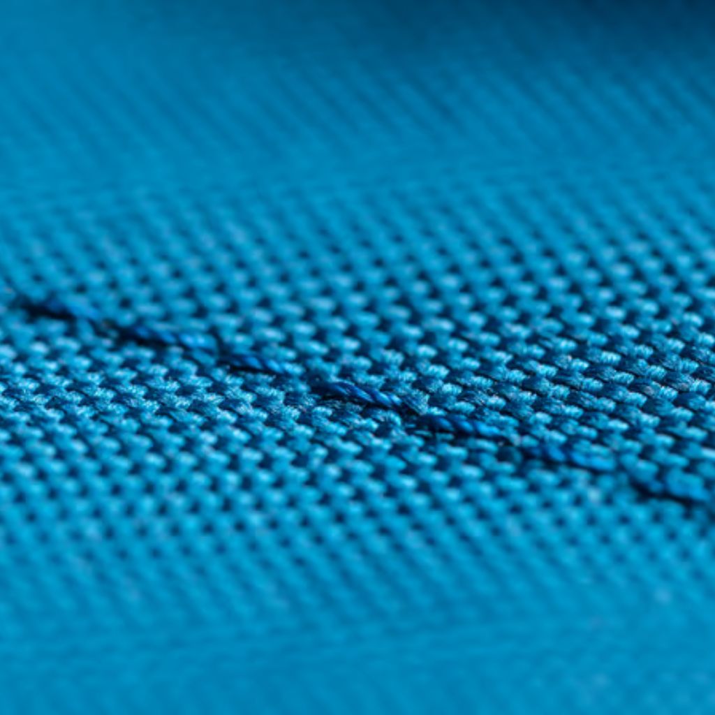 Close-up of blue woven fabric with a square pattern and a diagonal seam or line running across.
Aero Flex Pro Fabric: