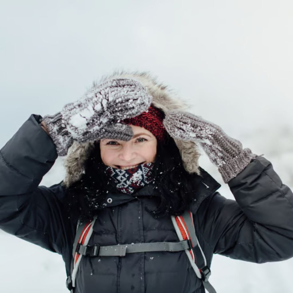 "Woman outdoors in a snowy setting adjusting a fur-trimmed hood of her dark winter jacket. She wears knit gloves and a patterned scarf, smiling at the camera."

Ultra-Warm Thermal Winter Coat: