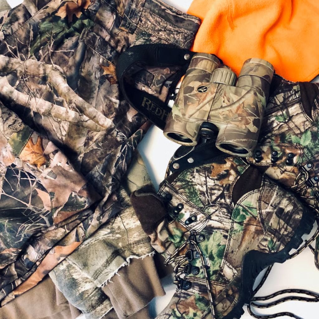 Alt text: A close-up view of a collection of camouflage-patterned winter jackets in various colors, including browns, greens, and oranges, layered together.

Arctic Shield Fabric: