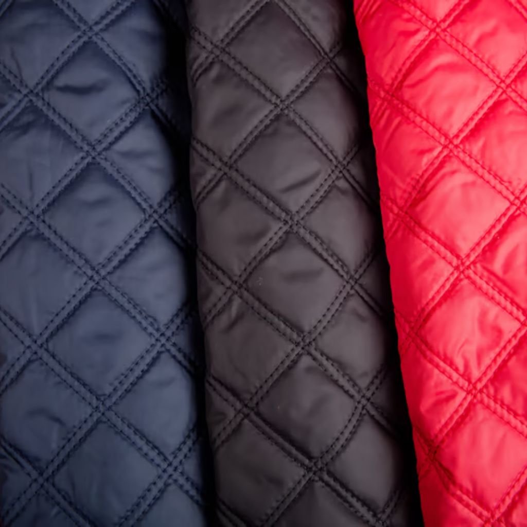 Storm Warm Insulation Fabric: Ultimate Winter Warmth Guide 7 Close-up of three quilted fabric panels in navy blue, black, and red, each with a diamond-stitched pattern and smooth, slightly glossy texture.
Storm Warm Insulation Fabric:
