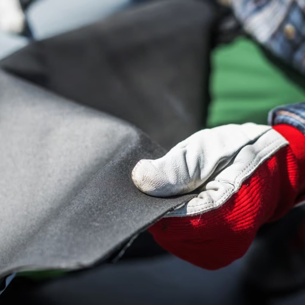 Polar Guard Heat Retention Fabric: Comfort Meets Performance 7 Alt text: Close-up of a gloved hand grabbing a black fabric. The glove has a white leather palm and fingers with a red knit cuff, and a blurred background of green and blue fabrics.
Polar Guard Heat Retention Fabric: