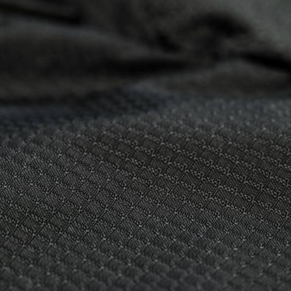 Alt text: Close-up of dark gray fabric with a small, repeating diamond/grid texture; a blurred section of the same fabric appears at the top.
What Is Thermo Guard Pro Fabric?