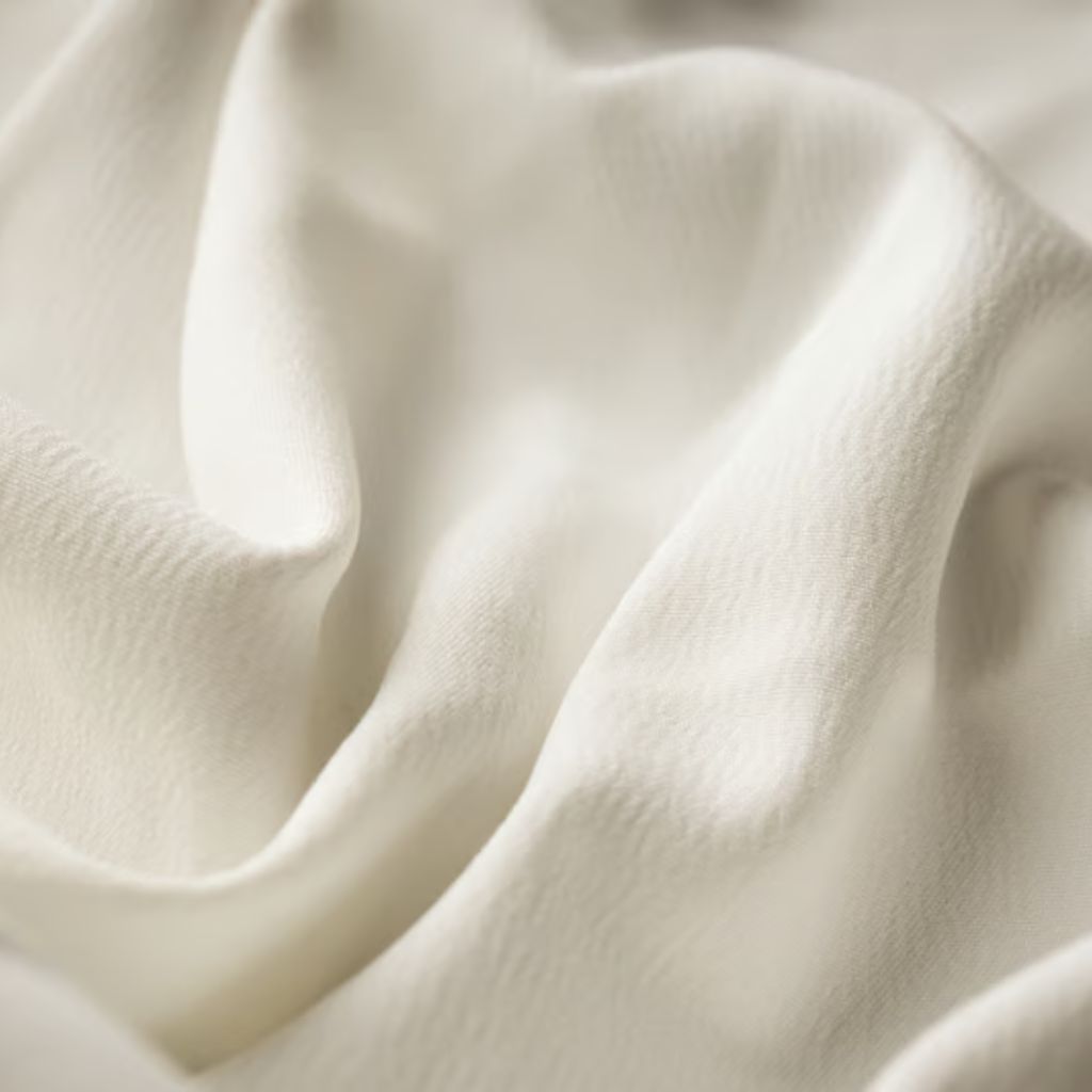 Alt text: Close-up of soft gray silk fabric with draped folds, showing subtle shadows and highlights that emphasize a smooth, luxurious texture.Alpine Silk Shield Fabric:
