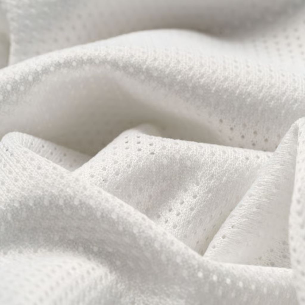 "Close-up of white porous knitted fabric draped and folded, showing shadows and highlights with small, evenly spaced holes."

Swift Fit Dynamic Fabric: