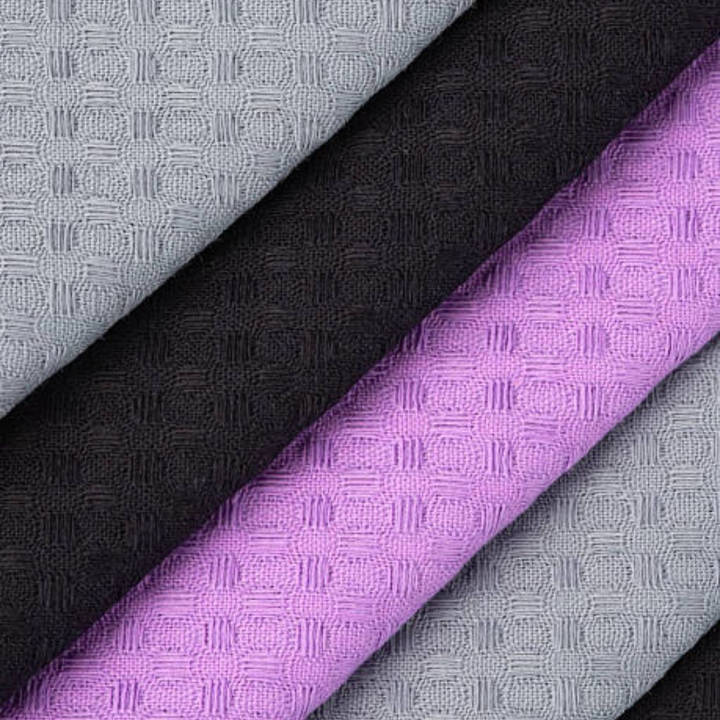 Close-up of folded textured fabrics in gray, black, and light purple, arranged diagonally with a small square-in-circle pattern.
Hyper Cool Performance Weave Explained: