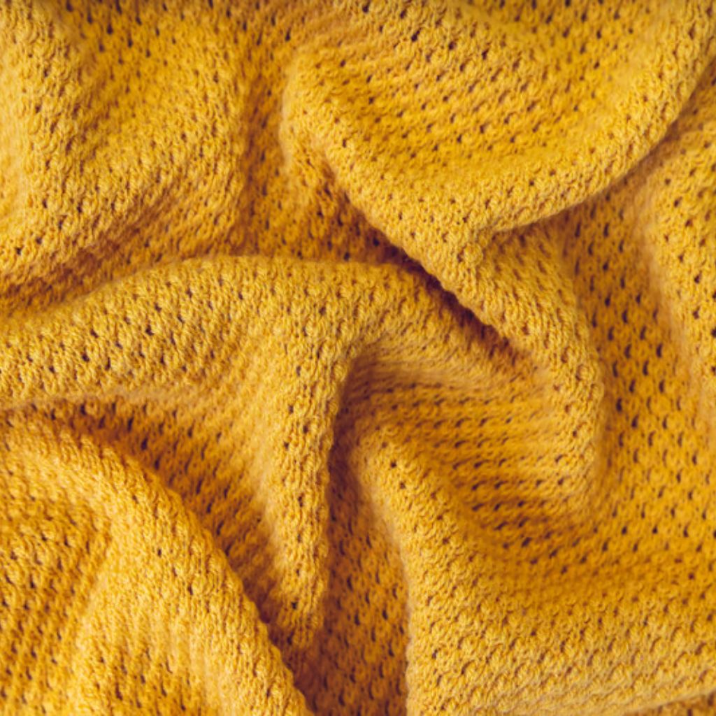 Fresh Vent Breathable Sports Cloth: Stay Cool While Active 7 "Close-up of folded, textured golden-yellow fabric with a slightly open weave and tiny holes, draped in soft folds."
Fresh Vent Breathable Sports Cloth: