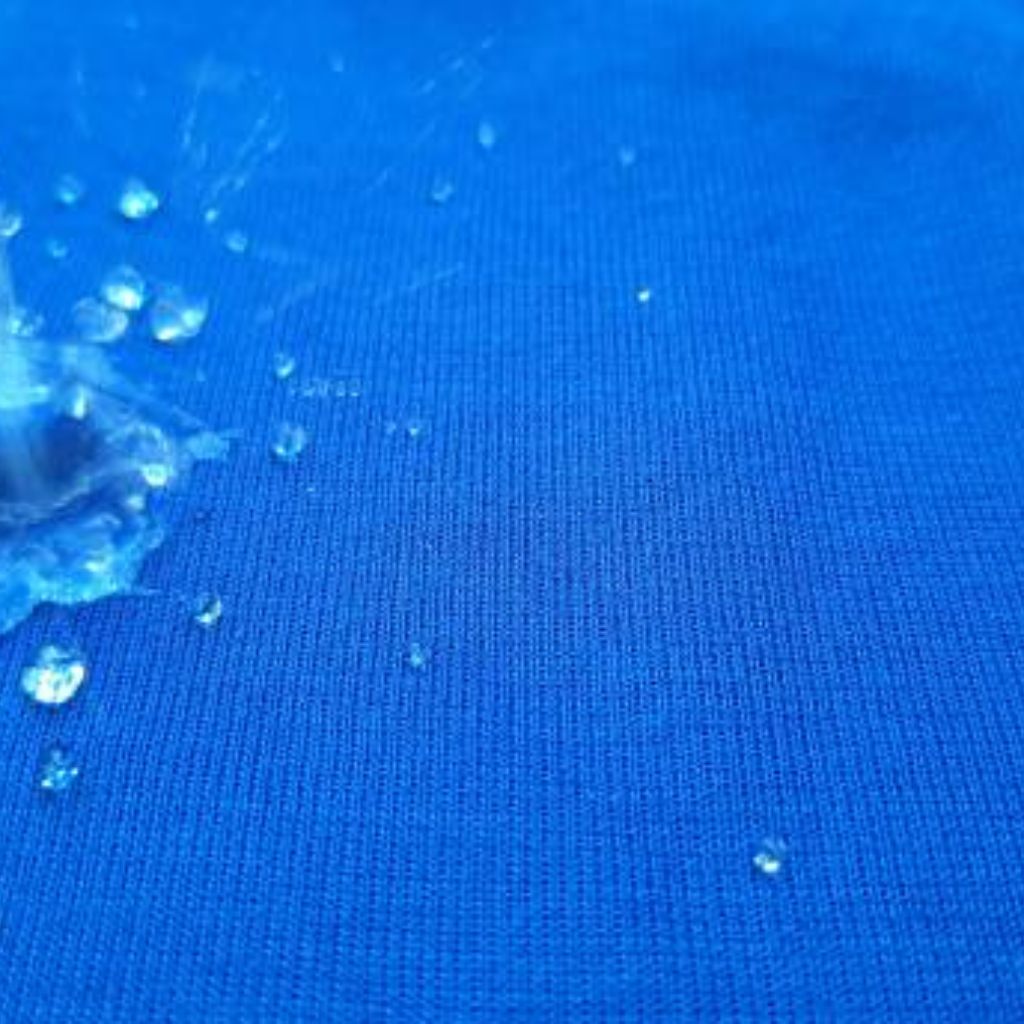 Close-up of blue fabric with scattered water droplets of varying sizes, some droplets appearing mid-air as if just splashed, revealing a fine woven texture.
Aqua Dry Cooling Active Fabric: