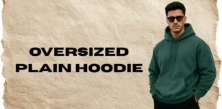 Oversized Plain Hoodie for Effortless Street Style A promotional image featuring a man wearing a dark green oversized plain hoodie with a front kangaroo pocket. He stands on the right, wearing sunglasses and black pants, with his hands in his pockets. The background is a textured light-brown paper-like surface, and bold black text on the left reads “OVERSIZED PLAIN HOODIE.