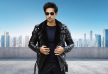 Premium Shirt Style Leather Jacket for Casual and Formal Looks A man stands on a rooftop overlooking a city skyline, wearing a black leather jacket with a fur collar, a black t-shirt, black pants, and sunglasses.
