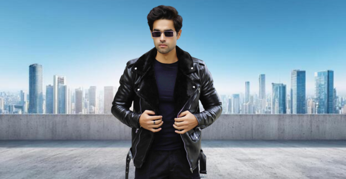 A man stands on a rooftop overlooking a city skyline, wearing a black leather jacket with a fur collar, a black t-shirt, black pants, and sunglasses.
