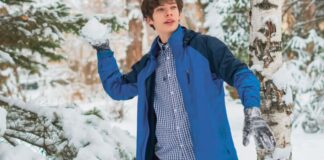 Storm-Guard Winter Coat: Best Choice for Cold Stormy Winters Alt text: "Young man outdoors in a snowy forest, throwing a handful of snow. He wears a blue shell jacket over a checkered shirt, with gray gloves." Storm-Guard Winter Coat