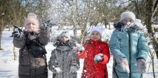 Weather-Resistant Winter Coat: Built for Wind, Rain and Snow Alt text (short description): Four people in winter jackets are playing in the snow, throwing powdery snow into the air. Weather-Resistant Winter Coat: