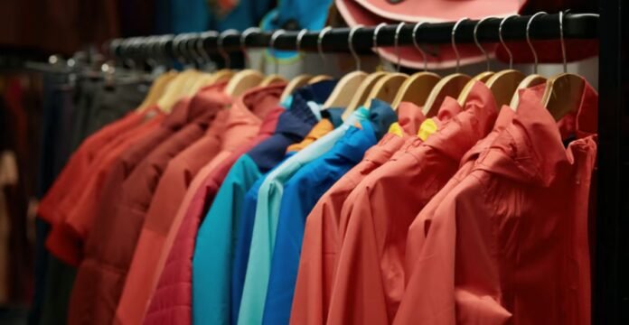 A rack of colorful jackets hanging on wooden hangers in a store or closet, featuring shades of red, pink, blue, and teal. How Gore-Tex Fabric Works: