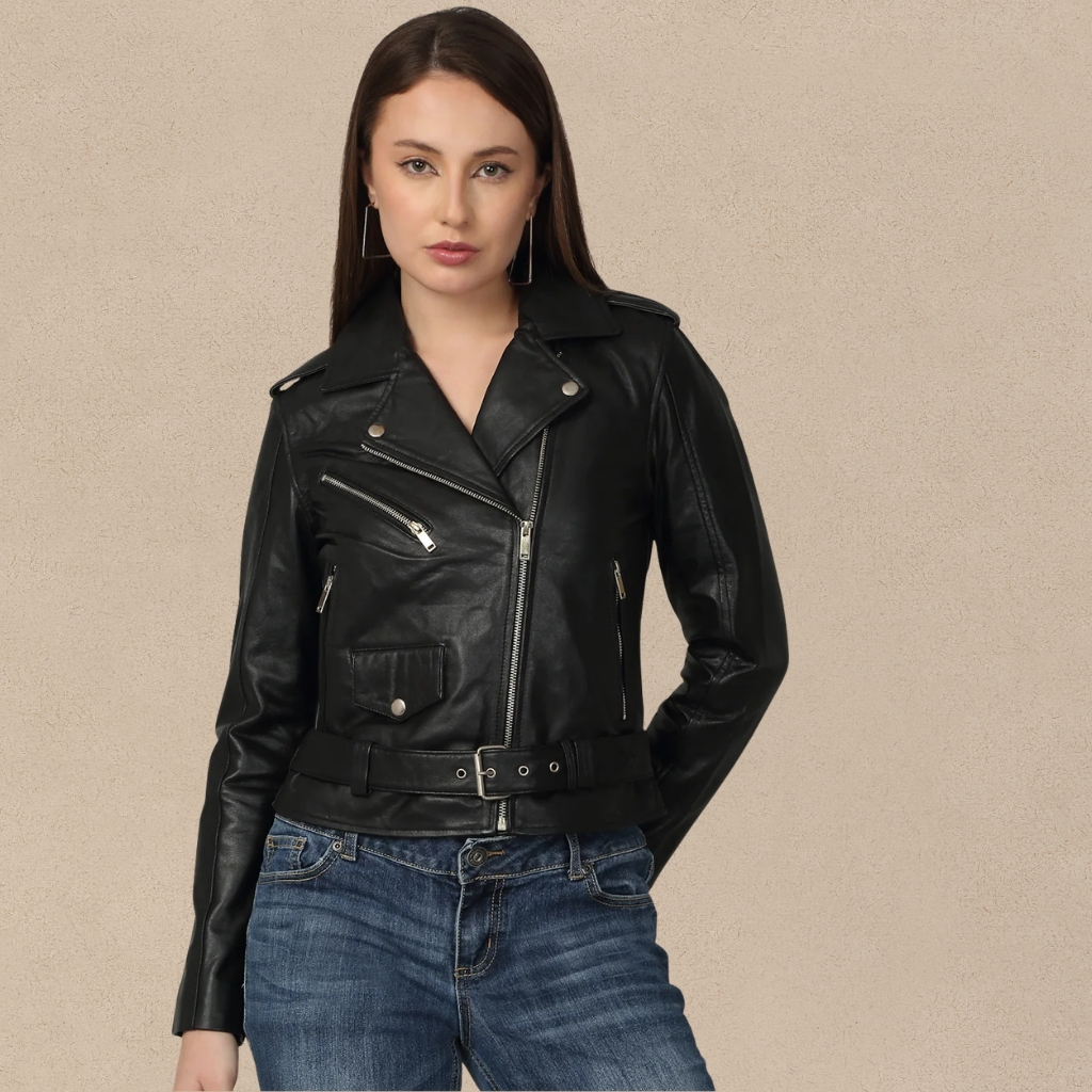 5 leather jacket for women Confidence & Style 6 A woman stands against a neutral backdrop wearing a black leather biker jacket with silver zippers and a belt, paired with blue jeans. She has long straight brown hair and square silver hoop earrings.5 leather jacket for women