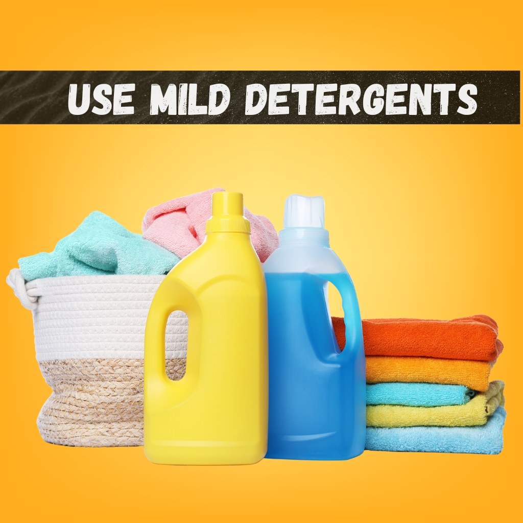Lightweight Zip Hoodie for Everyday Casual Comfort 6 A bright orange background with a basket of colorful towels on the left and two detergent bottles (yellow and blue) in front. A neat stack of folded towels in orange, yellow, blue, and green sits to the right. A bold black banner across the top reads โUSE MILD DETERGENTS.โ