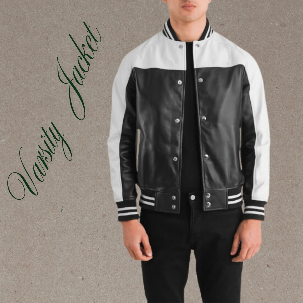 A person wearing a black and white varsity leather jacket with white sleeves and striped cuffs, standing against a neutral backdrop.
