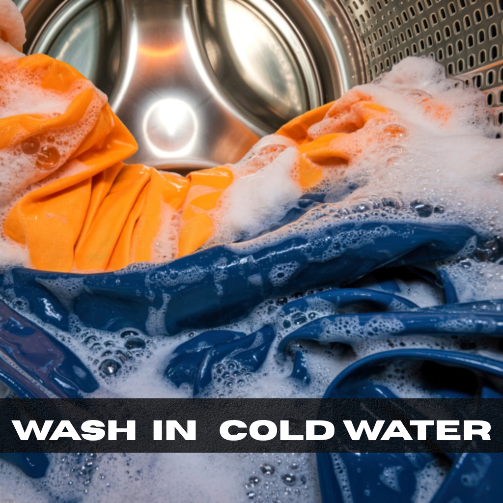 Inside a washing machine with blue and orange clothes and lots of soap bubbles; “WASH IN COLD WATER” text overlay.

