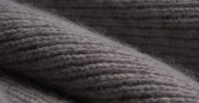 Close-up of gray knitted fabric showing textured ridges and soft fibers.