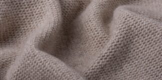 Woven Grade C Cashmere: Features & Benefits Woven Grade C Cashmere Close-up of beige knitted fabric with a visible textured knit pattern and soft folds.