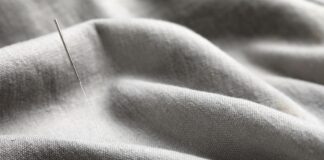 Woven Recycled Cashmere Fabric: Sustainable Luxury Woven Recycled Cashmere Fabric An acupuncture needle inserted into gray woven fabric, showing a thin silver needle with a textured handle amid softly draped folds.