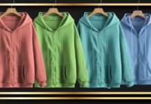 The Essential Zip-Up Plain Hoodie for Everyday Style Four zip-up plain hoodies in rose, green, teal, and blue hanging on wooden hangers against a dark, blurred background with gold accents; each hoodie features a zipper and two front pockets.