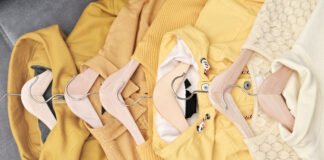 Abstract Graphic Hoodies: Bold Street Style Guide A row of yellow and cream-colored clothes on wooden hangers arranged on a gray surface.
