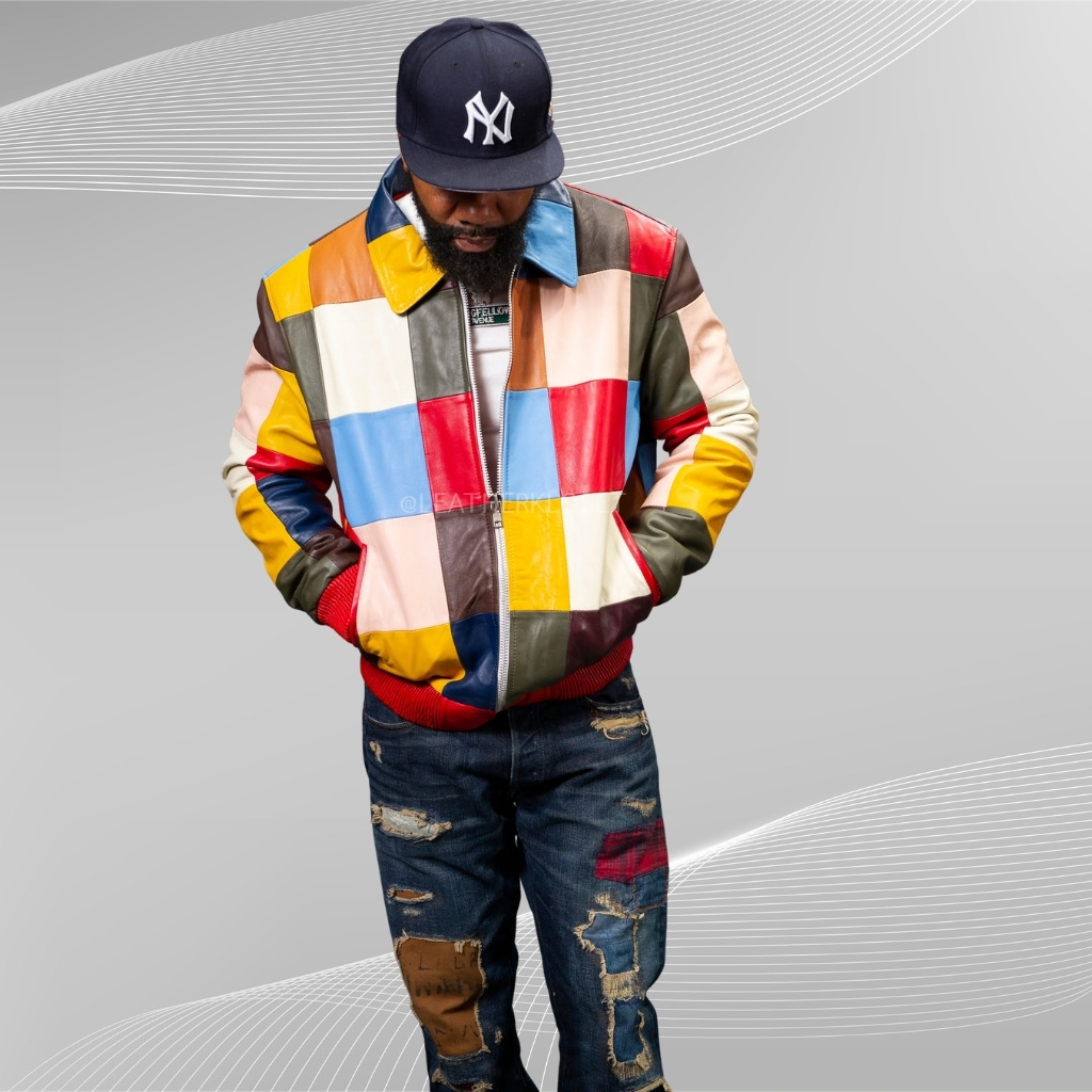Stylish Patchwork Leather Jacket with Bold Multicolor Design 4 A person wearing a multicolored patchwork leather jacket with red trim and distressed jeans stands against a gray backdrop. They wear a navy New York Yankees cap and have hands in the jacket pockets, head tilted downward.Stylish Patchwork Leather Jacket