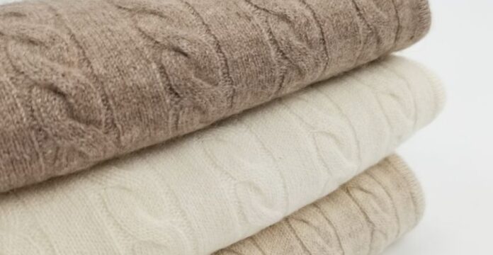 Close-up of blended cashmere wool fabric, showing the knit texture and folded layers in neutral beige and taupe tones.Types of Blended Cashmere Wool Fabric