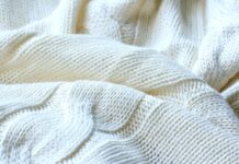 Cable Knit Pure Cashmere Fabric: Luxury Warmth Guide Cable Knit Pure Cashmere Fabric Close-up of a folded off-white cashmere blanket with a prominent cable knit pattern, showing textured stitches and depth from light and shadow.