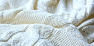 Cable Knit Pure Cashmere Fabric: Luxury Warmth Guide Cable Knit Pure Cashmere Fabric Close-up of a folded off-white cashmere blanket with a prominent cable knit pattern, showing textured stitches and depth from light and shadow.