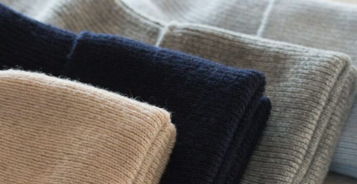 Cashmere-Cotton Blend Close-up of folded cashmere-cotton blend sweaters in beige, black, and gray.