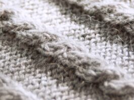 Cashmere Twill Fabric Guide Close-up of a grey knitted wool fabric with a textured cable knit pattern; soft, slightly fuzzy fibers with a subtle sheen.