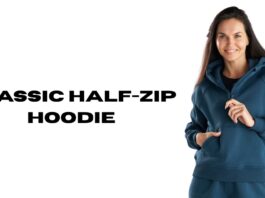 A woman wearing a teal-blue classic fleece half-zip hoodie, standing against a white background with text that reads ‘CLASSIC HALF-ZIP HOODIE’.