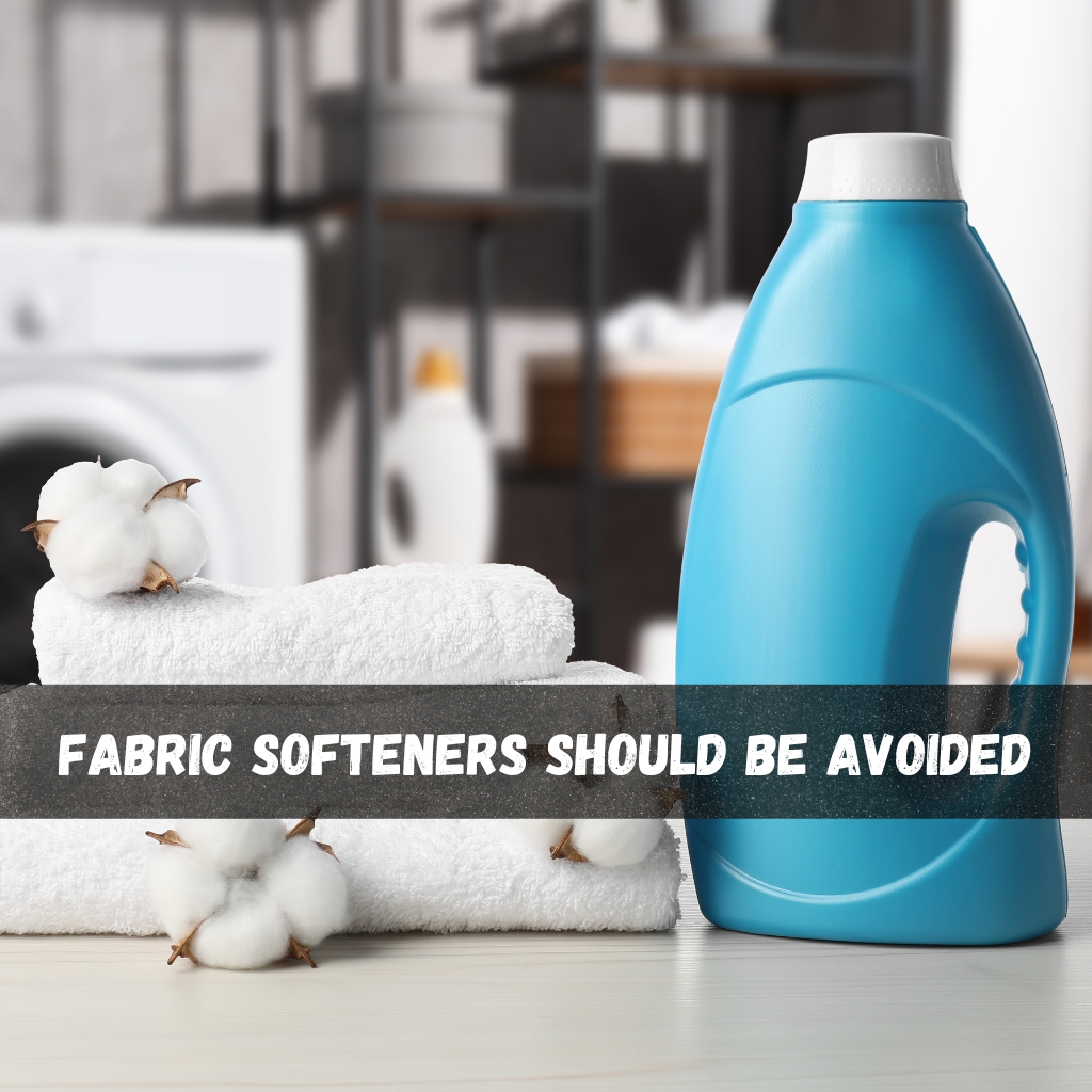 A laundry scene with a blue detergent bottle, white towels, and cotton bolls; a bold banner across reads “FABRIC SOFTENERS SHOULD BE AVOIDED.”