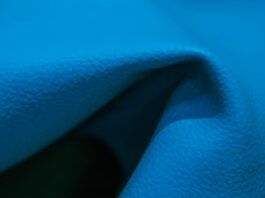 "Close-up of bright blue fabric with folds and shadows, showing a grainy texture and areas of light and dark."Swift Dry Athletic Performance Cloth: