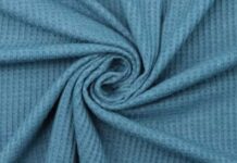 Power Stretch Active Fabric: Durable, Breathable & Flexible Close-up of light blue waffle knit fabric arranged in a swirling fold, showing a grid-like texture with shadows and highlights. Power Stretch Active Fabric: