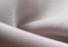 Flex Motion Stretch Fabric: The Future of Activewear Comfort Close-up of folded light grey fabric with a subtle texture and soft lighting. Flex Motion Stretch Fabric: