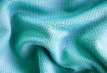 Fresh Flow Athletic Fabric: Why It’s Perfect for Activewear Close-up of light blue perforated fabric with soft folds, showing a mesh-like texture and small evenly spaced holes. Fresh Flow Athletic Fabric: