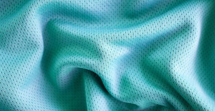 Close-up of light blue perforated fabric with soft folds, showing a mesh-like texture and small evenly spaced holes. Fresh Flow Athletic Fabric:
