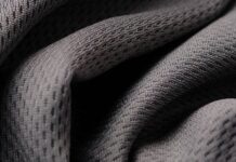 Hydro Wick Active Fabric: Stay Cool and Dry During Workouts Close-up of gray, porous fabric with a mesh-like weave, showing folds and shadows. Hydro Wick Active Fabric: