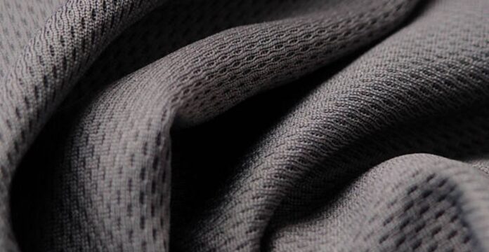 Close-up of gray, porous fabric with a mesh-like weave, showing folds and shadows. Hydro Wick Active Fabric: