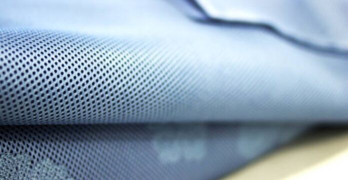 “Close-up of blue fabric with small perforated holes, likely a quilted or textured winter coat material.” Breeze Tech Training Fabric: