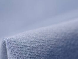 Alt text: “A close-up view of a soft, blue knit fabric that resembles the texture of a winter coat or warm fleece, with a rolled edge in the foreground.” Frost Flex Active Fabric: