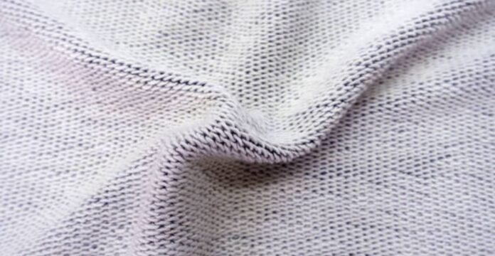 Close-up photo of light gray knit fabric with a textured, slightly wrinkled surface and visible interwoven stitches. Dry Flow Cooling Knit: