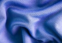 Vapor Flow Athletic Fabric: Lightweight Fabric for Training A close-up photo of a textured, blue fabric with a smooth, crumpled surface, showing small perforations or mesh-like holes. Vapor Flow Athletic Fabric: