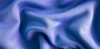 Vapor Flow Athletic Fabric: Lightweight Fabric for Training A close-up photo of a textured, blue fabric with a smooth, crumpled surface, showing small perforations or mesh-like holes. Vapor Flow Athletic Fabric: